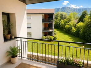 Un balcon avec vue sur une montagne, un pot de fleurs et un parterre.