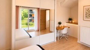 Un dormitorio moderno con una cama grande, un escritorio y vistas a un balcón.