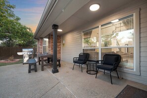 Covered patio with cozy seating, outdoor dining & BBQ grill.
