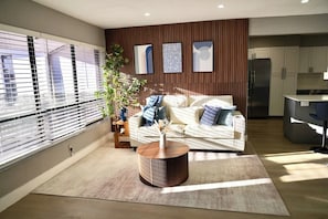 A modern living room with a sofa, a coffee table, and a kitchen area in the background. - Family Pool Oasis Near Hard Rock • Beaches • Airport (Hollywood)