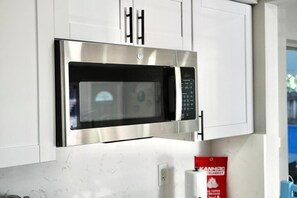 A stainless steel microwave oven mounted on a white cabinet with a control panel. - Family Pool Oasis Near Hard Rock • Beaches • Airport (Hollywood)