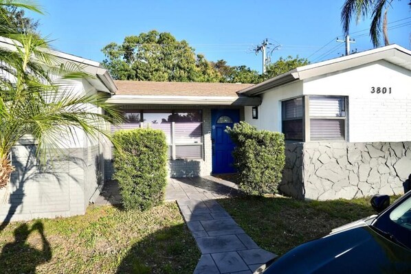 A residential property with a garage, a blue door, and a stone wall. - Family Pool Oasis Near Hard Rock • Beaches • Airport (Hollywood)