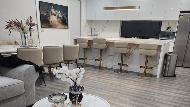 A modern living room with a sofa, coffee table, and a dining area with chairs.