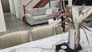 A modern living room with a marble table, a sofa, and a staircase.