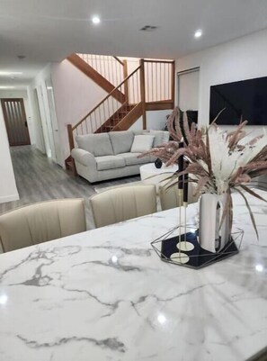 A modern living room with a marble table, a sofa, and a staircase.