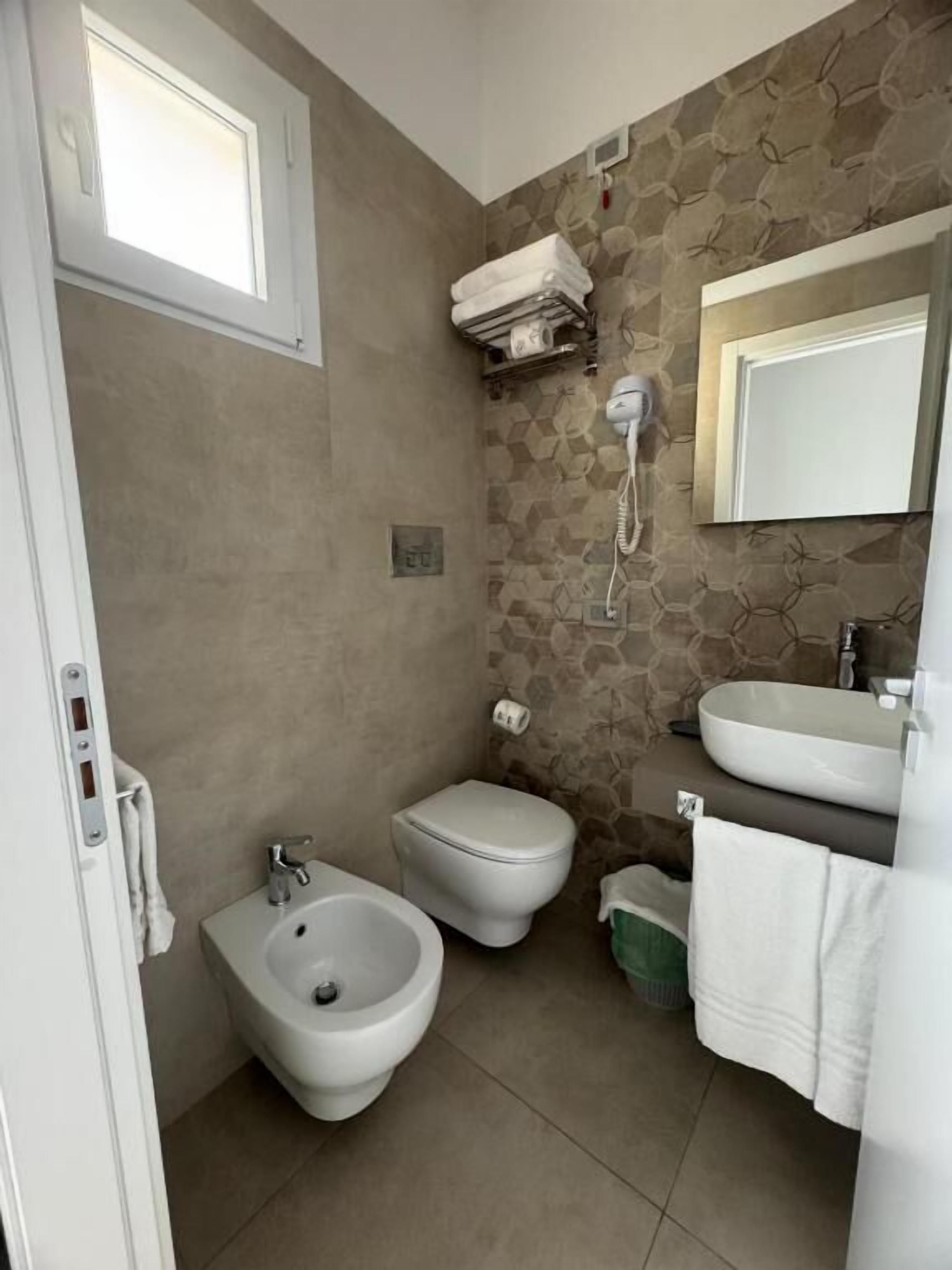 A bathroom with a bidet, toilet, and sink.