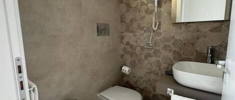 A bathroom with a bidet, toilet, and sink.