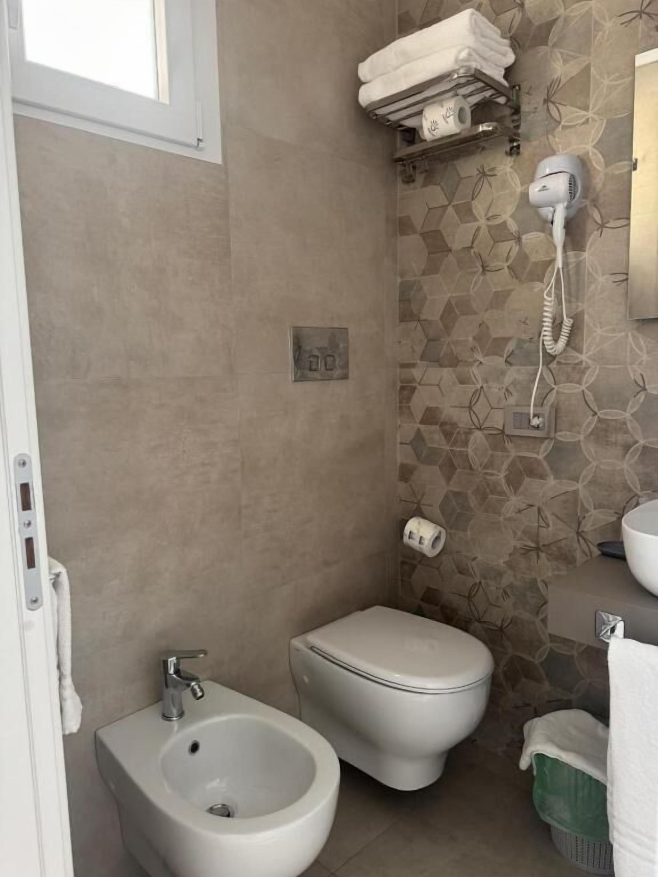 A bathroom with a bidet, toilet, and a towel rack.