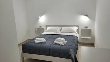Una camera da letto moderna con un letto, due comodini e un tavolino da notte.