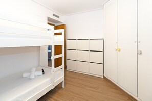 Een stapelbed met opbergladen, een garderobe met verschillende vakken en een deur met slot.