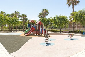 Ein Spielplatz mit Rutsche, Klettergerüst und Schaukeln.