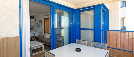 A dining area with a table and chairs, a sliding glass door leading to a kitchen, and a view of the outside.