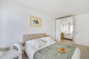 A bedroom with a bed, a chair, a wardrobe, a mirror, and a painting on the wall. - Spacious Apartment 1br/2p - Auteuil (Paris)