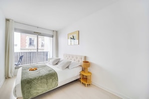 A bedroom with a bed, a bedside table with a lamp, a window with curtains, and a view of the outside. - Spacious Apartment 1br/2p - Auteuil (Paris)