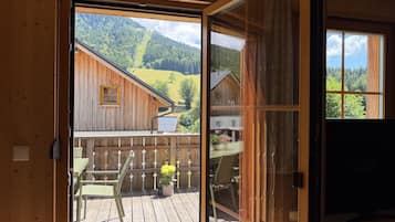 Une cabane en bois dotée d’une porte-fenêtre coulissante qui donne sur une terrasse extérieure avec une table et des chaises.