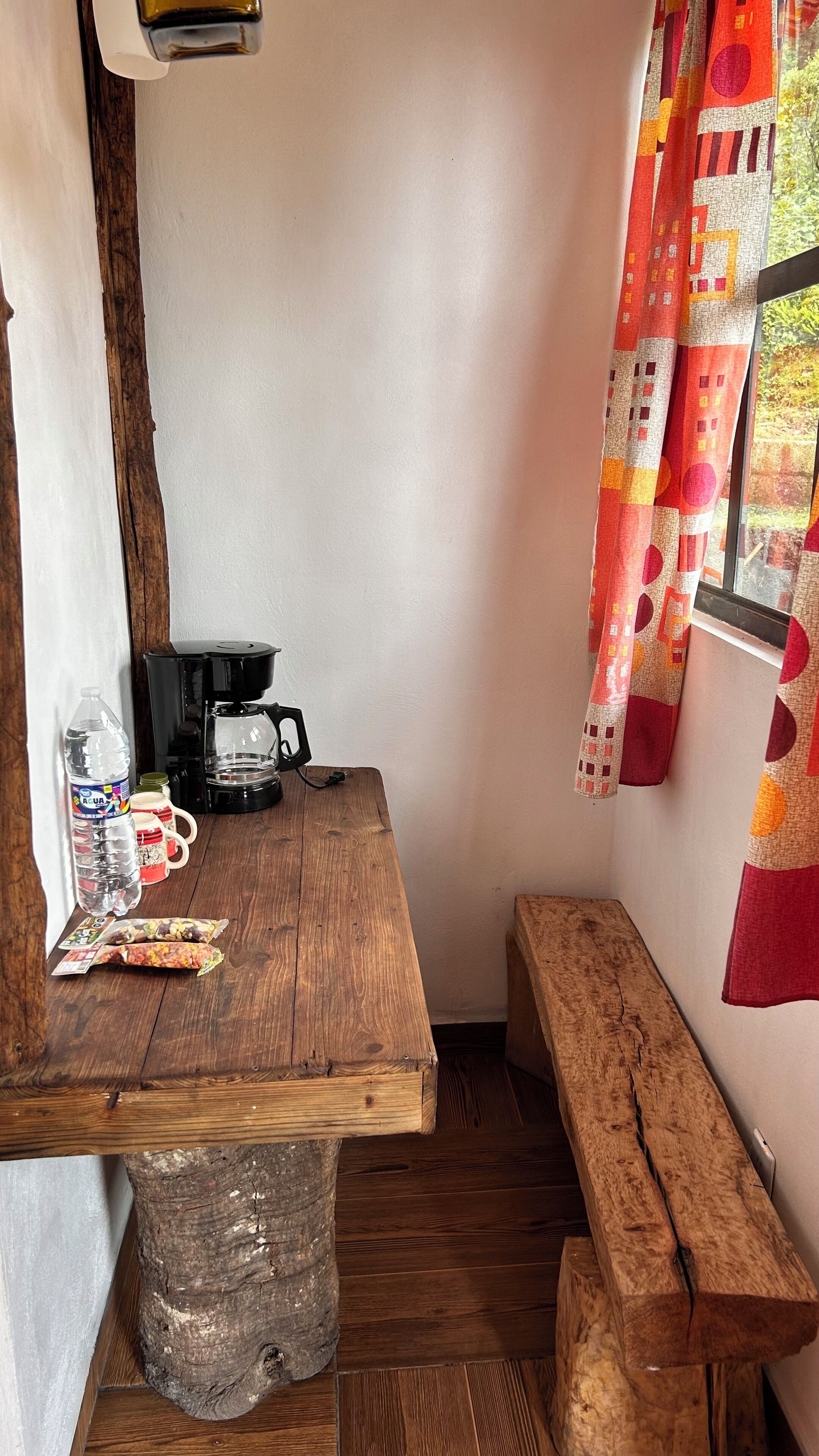 Una cocina pequeña y rústica con una mesa de madera, una cafetera y un banco.