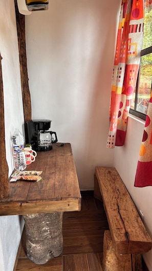 A small, rustic kitchen with a wooden table, a coffee maker, and a bench. - Hospedaje La Joya By GEstores (Mineral del Chico)