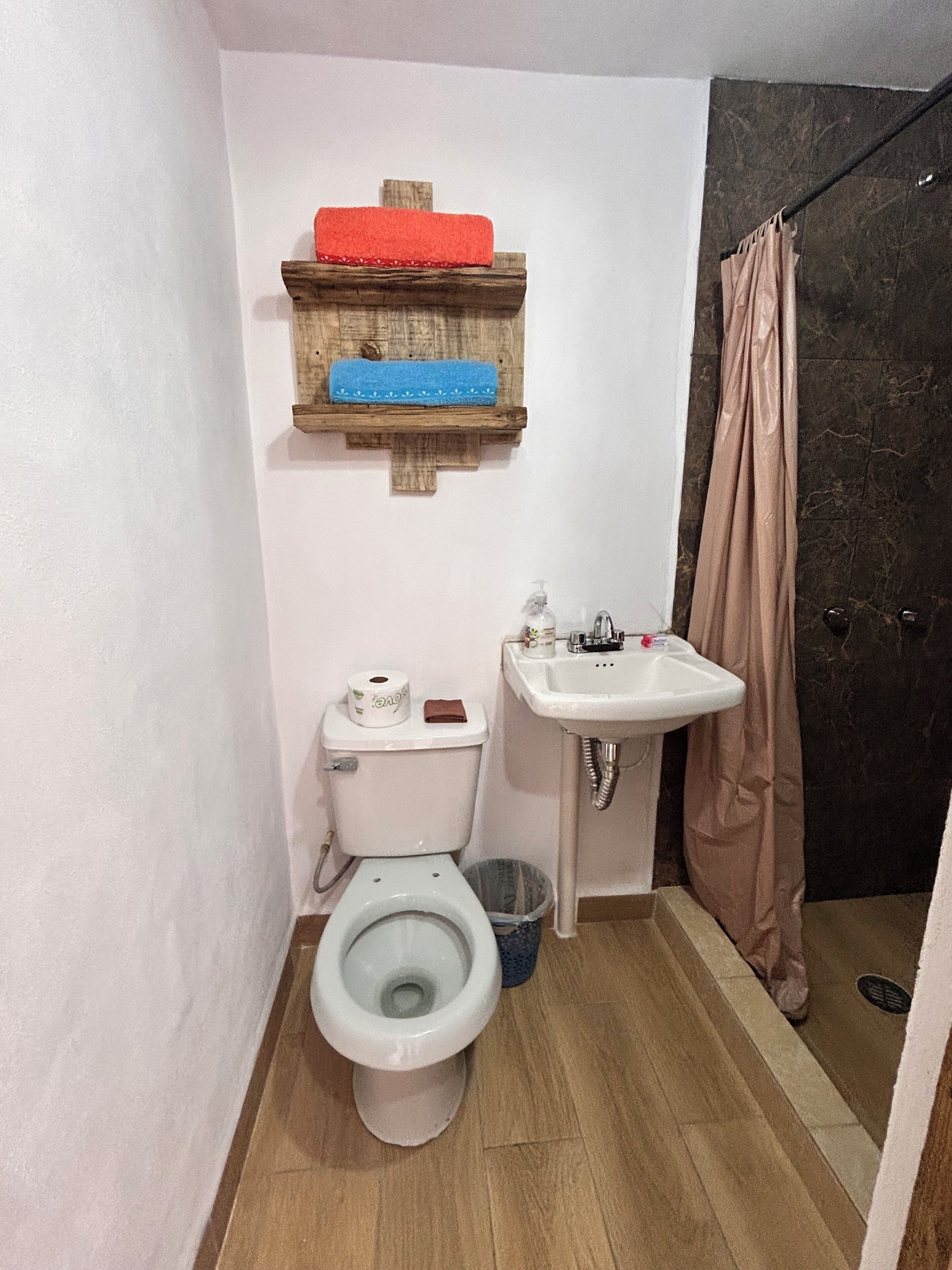 A compact bathroom with a toilet, sink, and shower area.