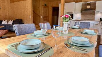 Un intérieur en bois comprenant une table à manger pour quatre personnes, un canapé et un coin cuisine.