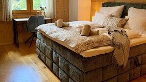A bedroom with a large bed, a desk, and a window with curtains. - Hideaway Chalets Loser - 5 (Altaussee)