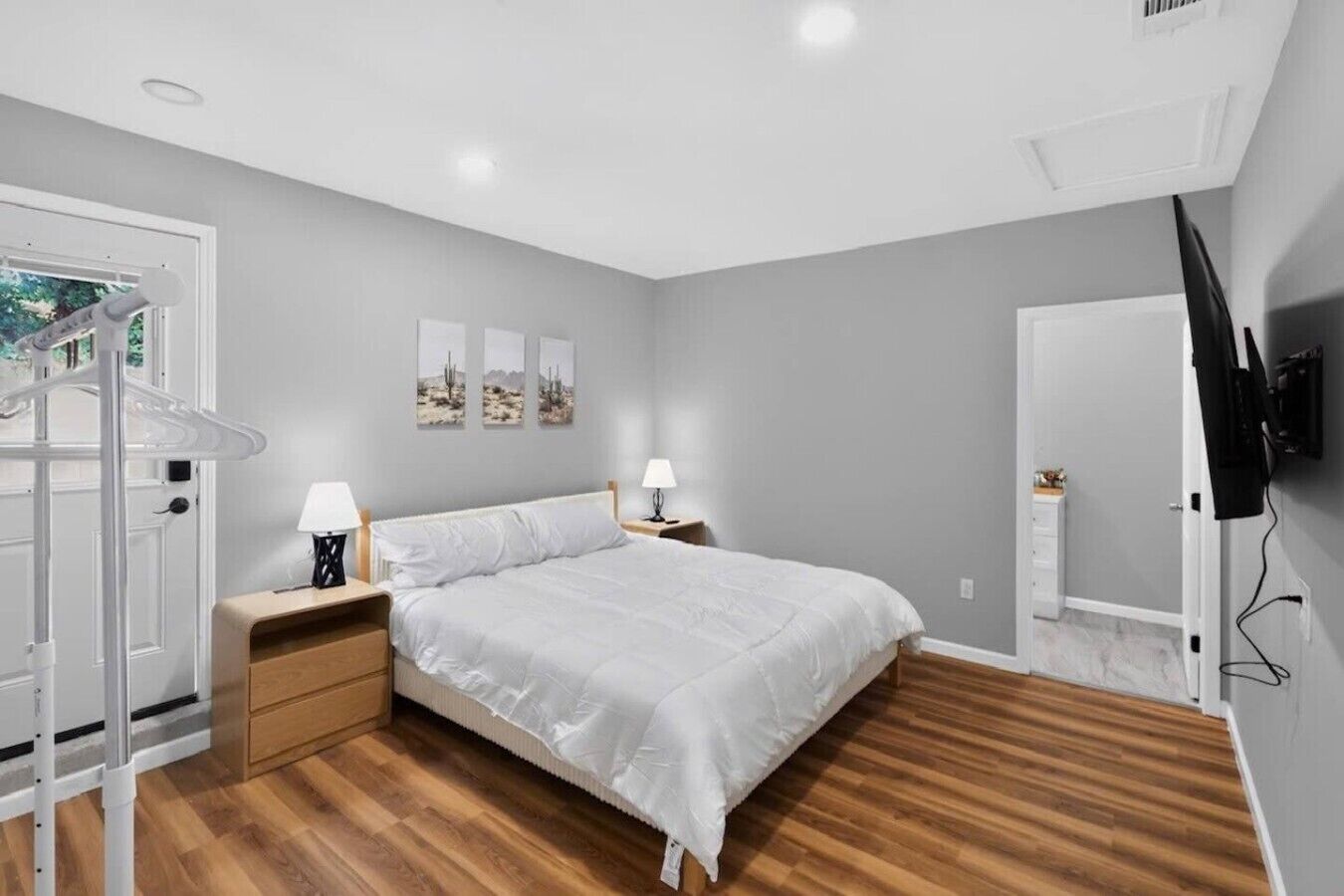 Quarto com cama, mesas de cabeceira, televisão e guarda-roupa.