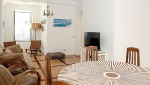 Una sala de estar con sofá, sillas, televisor y una mesa de comedor.