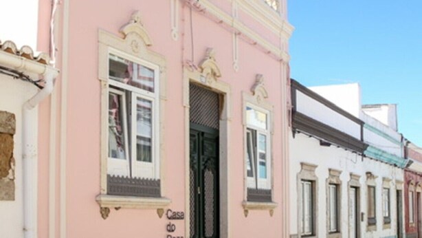 Un edificio rosa con puerta, ventanas y cartel que dice 'Casa do Povo'.
