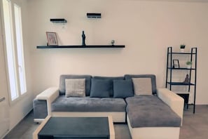 Ein modernes Wohnzimmer mit einem grauen Ecksofa, einem schwarzen Couchtisch und einer schwarzen Wandregal.