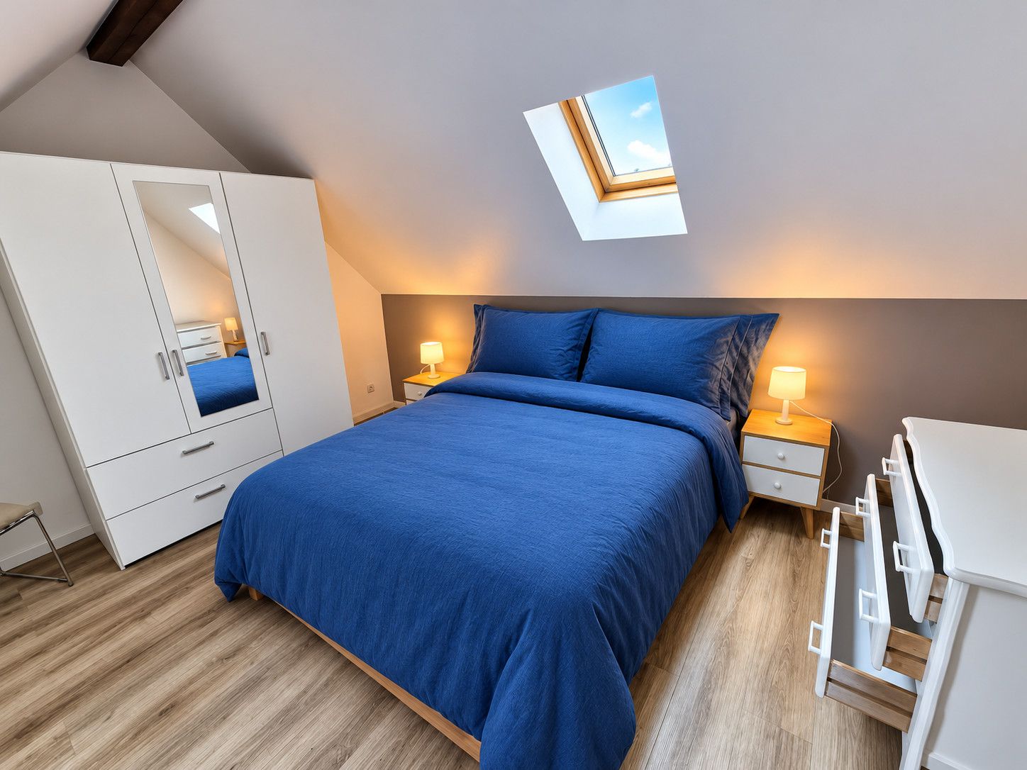 A bedroom with a bed, bedside tables, a wardrobe, and a skylight.
