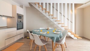 A modern kitchen with a dining area, a staircase, and a view of the upper floor. - Elsa's House, Algarve, Faro (Faro)