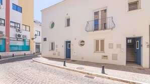 A cobblestone street with a building featuring a blue door, a balcony, and a small window. - Elsa's House, Algarve, Faro (Faro)