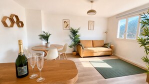 A modern living room with a wooden dining table, a sofa, and a large window. - Apartment with a terrace in Cannes (Cannes)