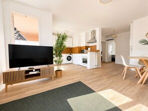 Eine moderne Wohnung mit Wohnzimmer, Küche, Essbereich und einem Flur, der zum Schlafzimmer führt.