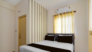 A bedroom with a bed, a window with curtains, a door, and a wall-mounted air conditioner. - Classic Red Cherry Wagtail (Bengaluru)