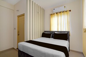 A bedroom with a bed, a window with curtains, a door, and a wall-mounted air conditioner. - Classic Red Cherry Wagtail (Bengaluru)