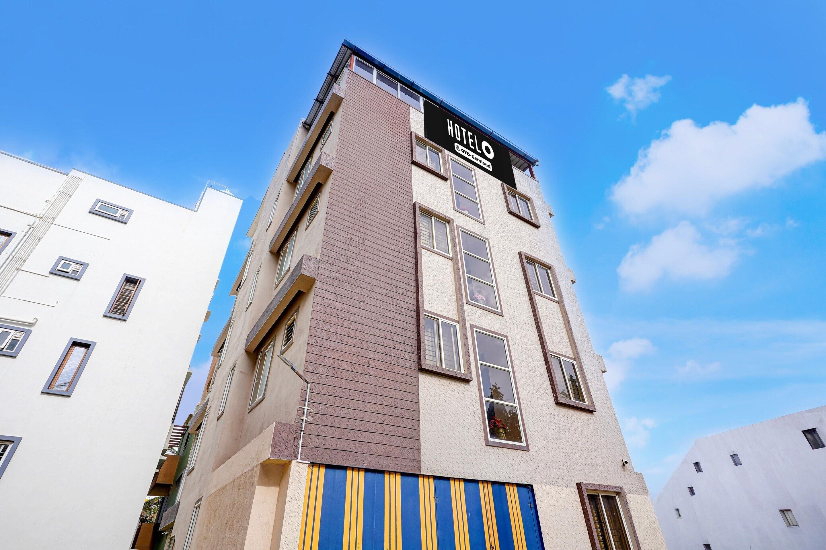 A multi-story hotel building with a sign indicating it is serviced by a specific company.