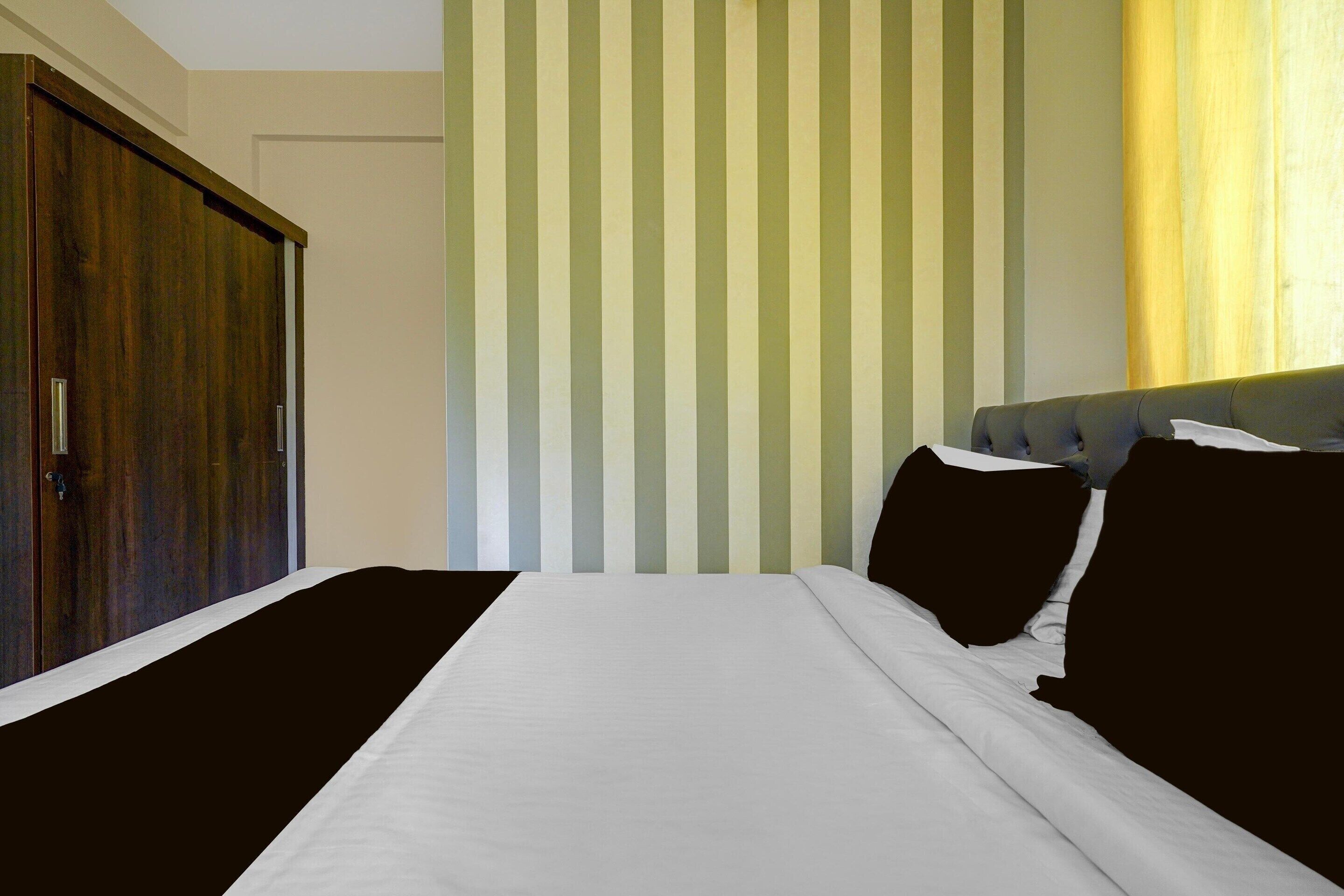 A bedroom with a bed, a wardrobe, and a striped wall.