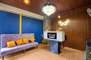 A hotel reception area with a purple sofa, a chandelier, and a sign that reads 'HOTELO OYO-Serviced.' - Classic Red Cherry Wagtail (Bengaluru)