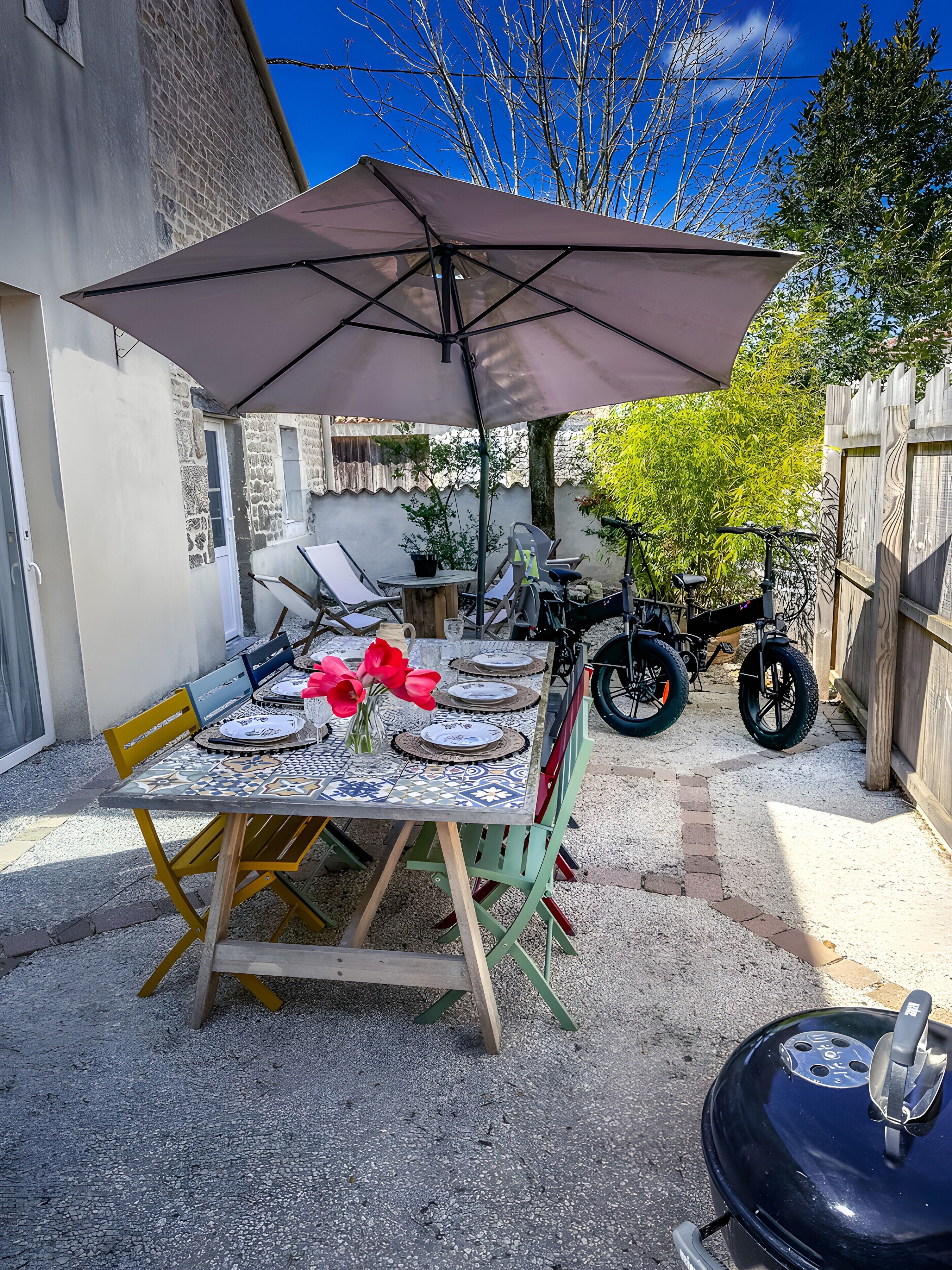 A patio with a table set for four, a barbecue grill, and a bicycle.