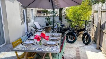 A patio with a table set for four, a barbecue grill, and a bicycle.