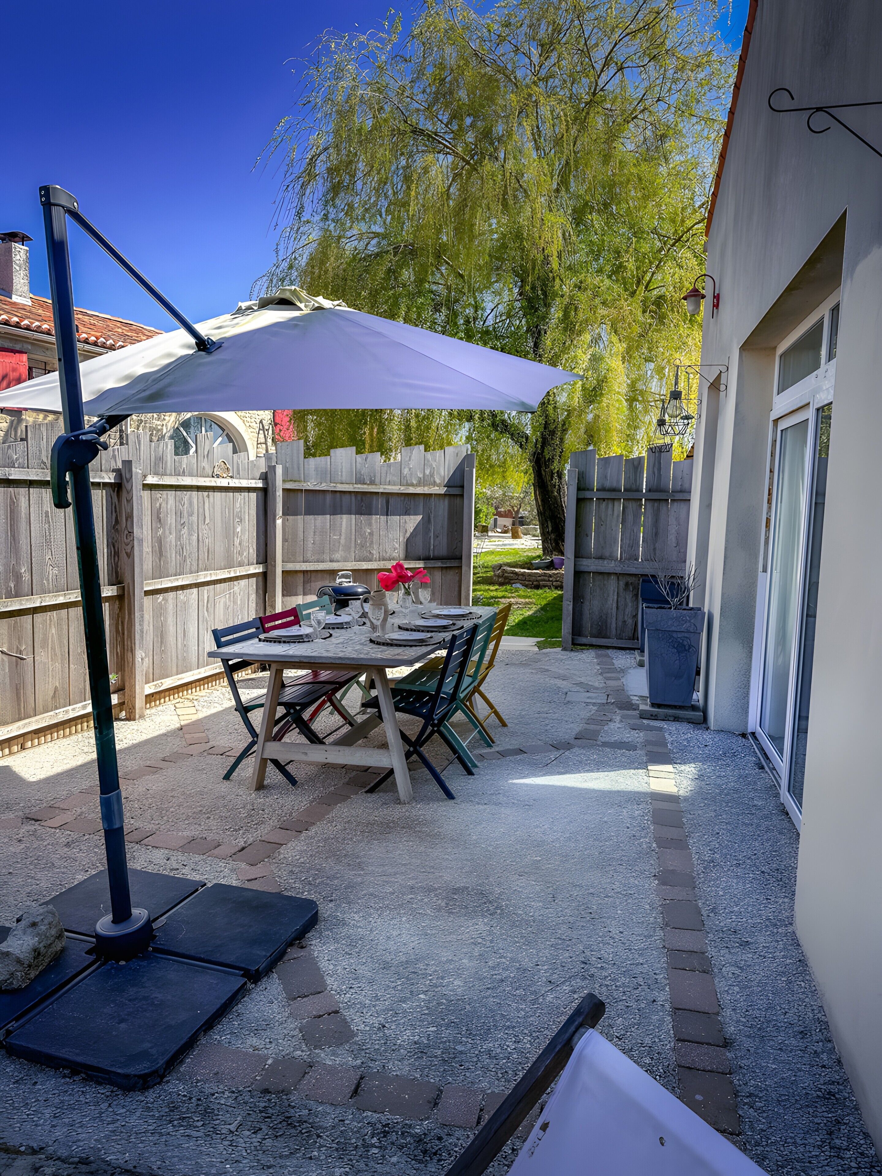 En patio med et spisebord, en markise og et træhegn i baggrunden.