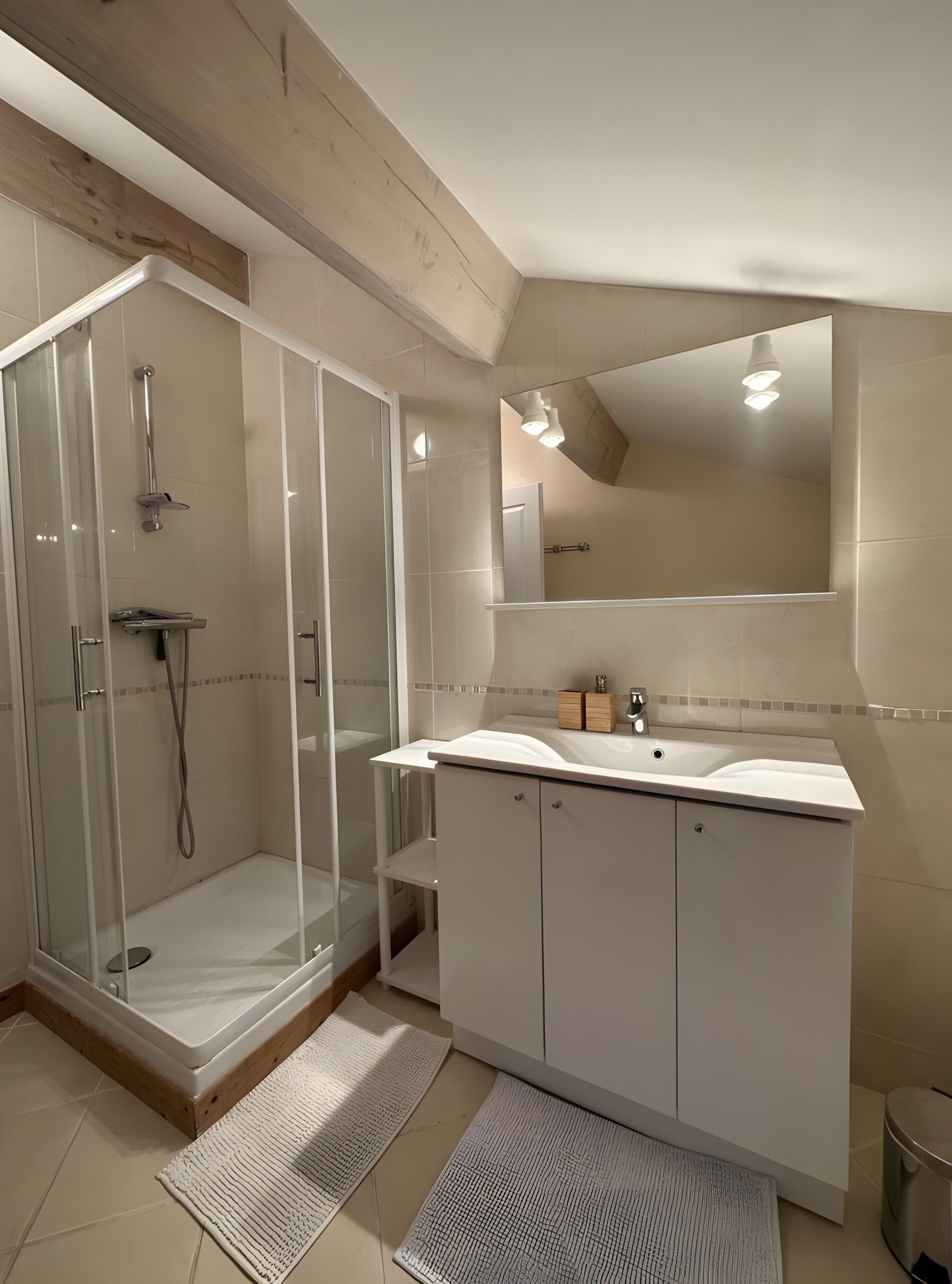 A modern bathroom with a glass-enclosed shower, a vanity with a mirror, and a tiled floor.