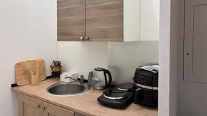 A compact kitchen with a wooden cabinet, a sink, a coffee maker, and a toaster. - Charming flat in Avignon shopping streets (Avignon)