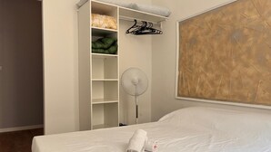 A bedroom with a bed, a white wardrobe with shelves, a hanging rack, and a large abstract painting on the wall. - Charming flat in Avignon shopping streets (Avignon)