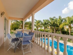 Ein Balkon mit Pool, Palmen und einem Tisch mit Stühlen.