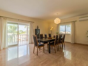 A dining area with a table and chairs, large windows, and a view of the outdoors. - V5 Alvor by Interhome (Alvor)