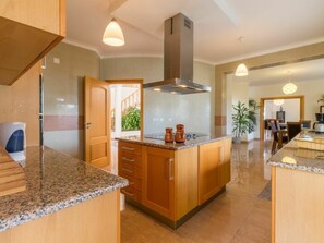 A kitchen with wooden cabinets, granite countertops, a stainless steel range hood, and pendant lighting. - V5 Alvor by Interhome (Alvor)