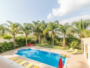 Ein Pool mit Liegestühlen und Palmen.