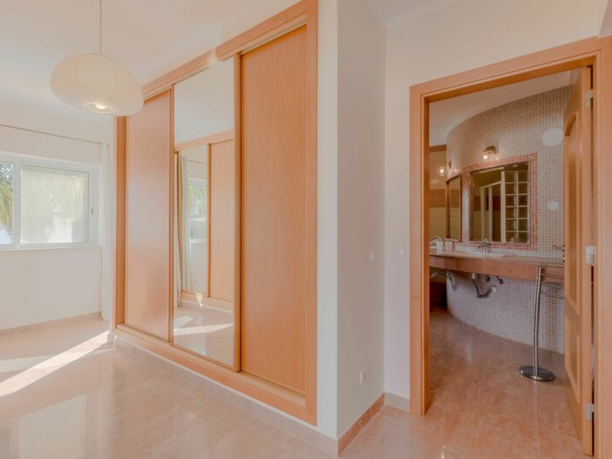 A modern interior with a sliding door, a bathroom with a tiled wall, and a visible shower area.