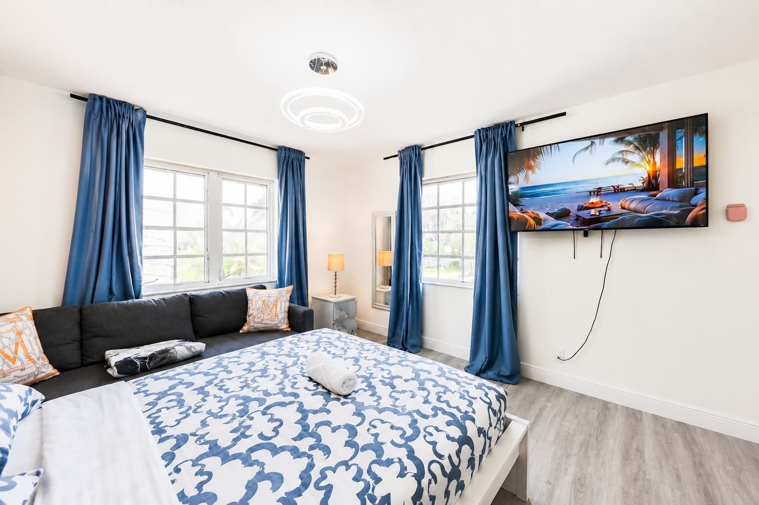 Ein Hotelzimmer mit einem Bett, einer Couch, einem Fernseher und einem Fenster mit Vorhängen.